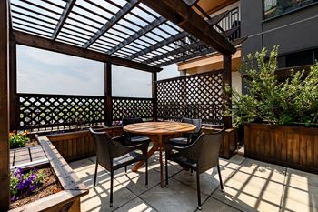 A patio with a table and chairs under a wooden roof.at Raymond Block, Edmonton, AB